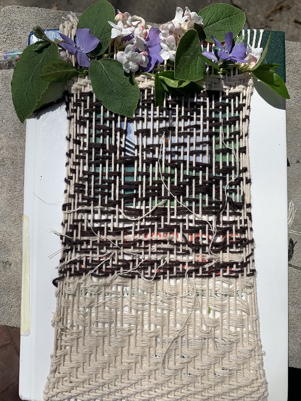 maroon and cream weaving over white book cover with violet and white flowers and leaves at the top