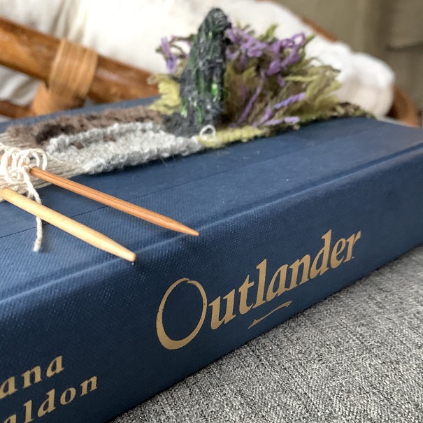 purple, green, white, and brown weaving over blue hardcover Outlander
