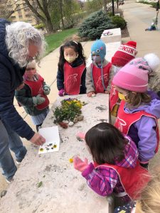 Several students of the CDL press flowers while gathered around a stone bench outdoors