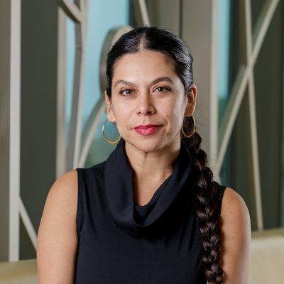 Portrait of Carolina Sarmiento, a Chicana woman, with a dark brown braid and black dress.