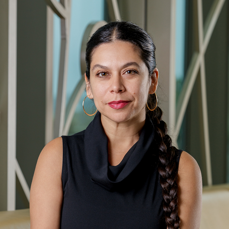 Portrait of Carolina Sarmiento, a Chicana woman, with a dark brown braid and black dress.