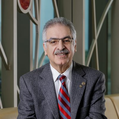 A Caucasian man smiling, wearing with a suit and striped tie.