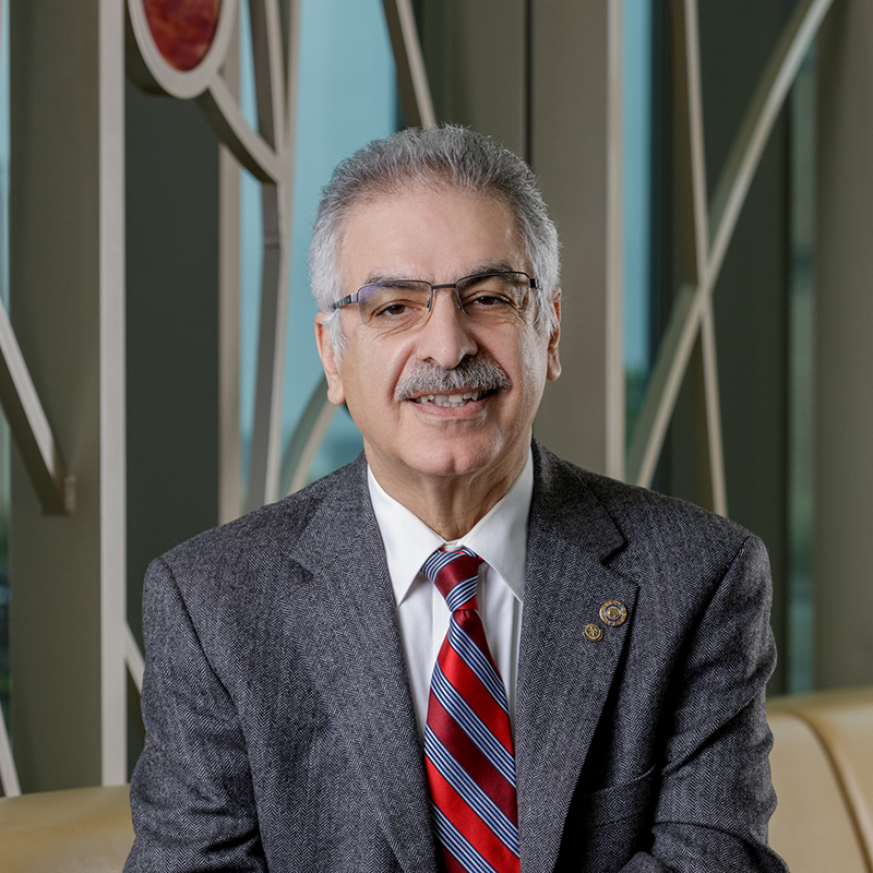 A Caucasian man smiling, wearing with a suit and striped tie.