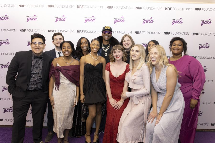 12 people, formally dressed, pose as a group in front of an NRF Foundation gala background.