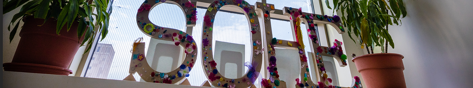 Letters SoHE in front of a window with a plan on each side.