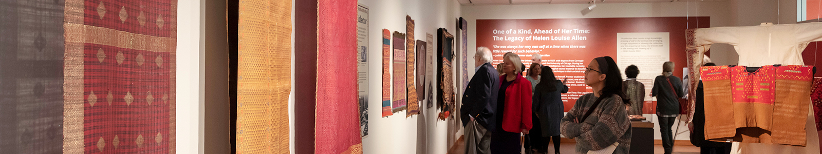 Gallery with many people looking at textiles hanging on the walls.