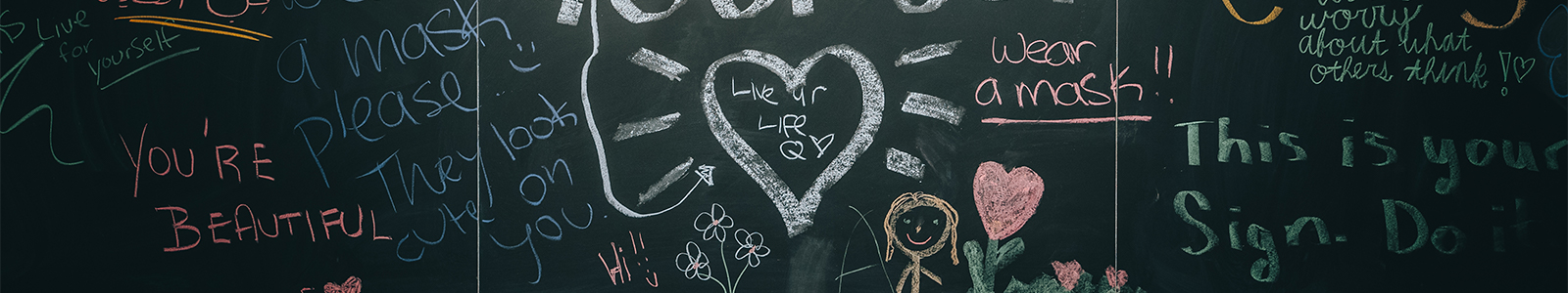 A black chalkboard with lots of colorful, positive handwritten messages. There is a large heart in the center.