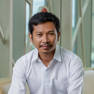 Portrait of Sarakk Rith, a man with black hair, wearing a white shirt, black pants, and a watch.