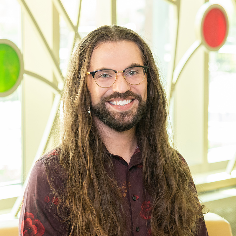 Professional photo of a person with brown hair smiling in front of 100 Women Wall.