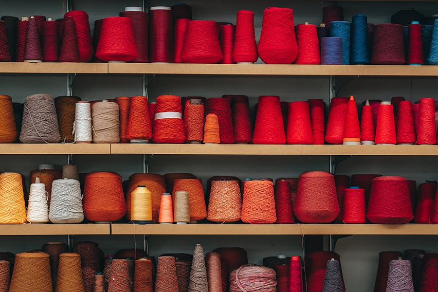 Four wooden shelves filled with of red and brown spools of thread