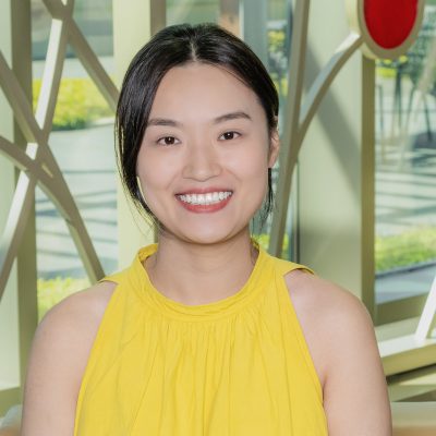 An Asian woman smiling, with black hair, wearing a yellow dress.