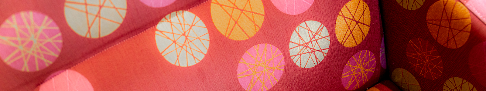 A circle pattern of pink, yellow and light blue circles on a red background.