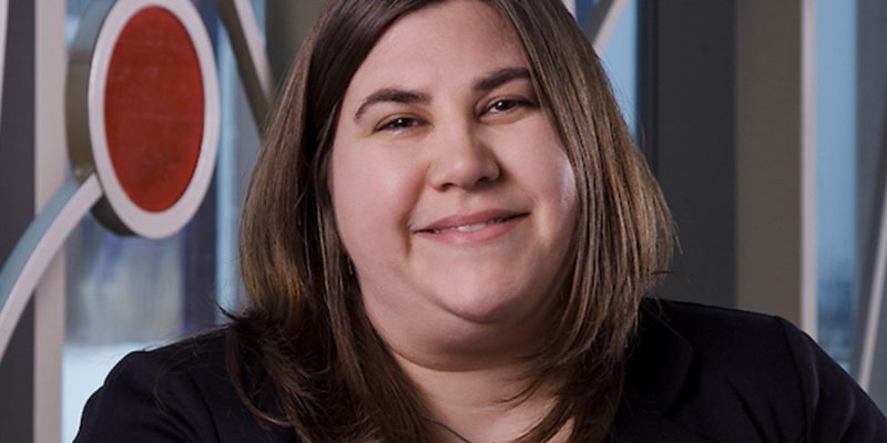 A woman smiling, with shoulder-length brown hair, wearing a black blazer.