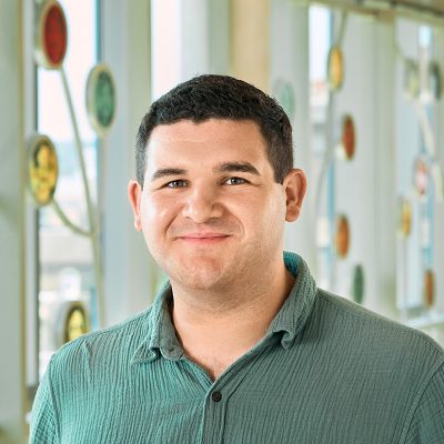 A white man with brown hair, smiling, wearing a green shirt.