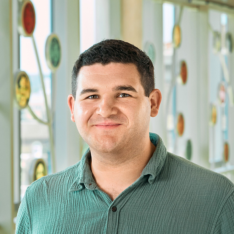 A white man with brown hair, smiling, wearing a green shirt.