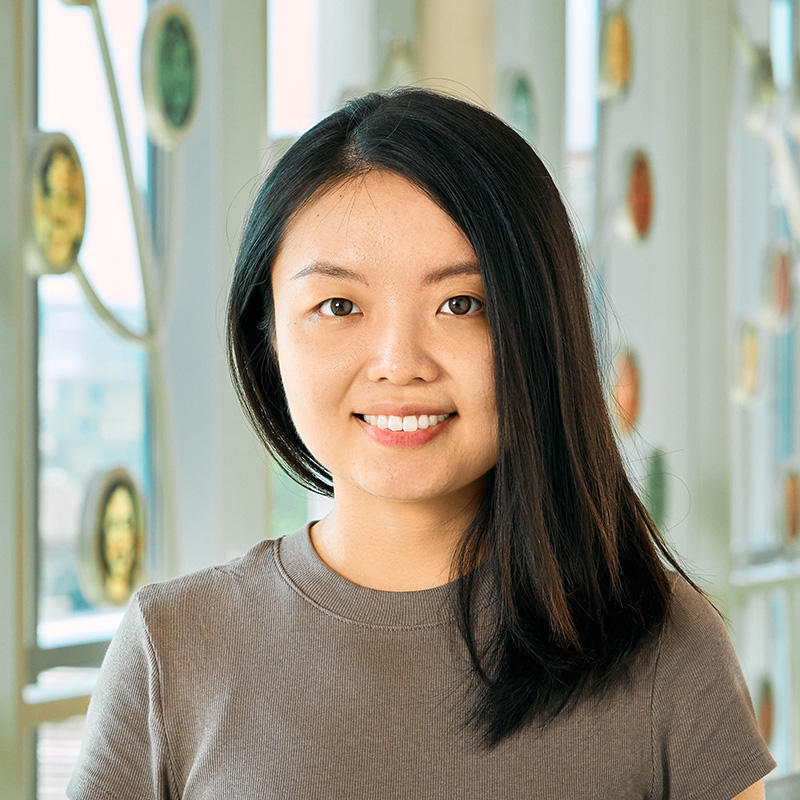 An Asian woman smiling, with black, straight hair, wearing a grey shirt.