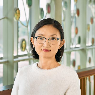 An east Asian woman with short black hair with a white sweater and silver earrings.