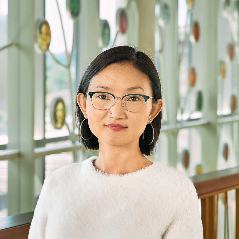 An east Asian woman with short black hair with a white sweater and silver earrings.