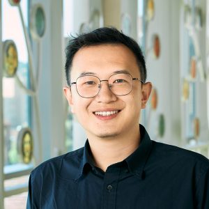 An Asian man with black hair and black eye color, wearing a dark blue shirt.