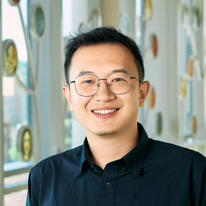 An Asian man with black hair and black eye color, wearing a dark blue shirt.