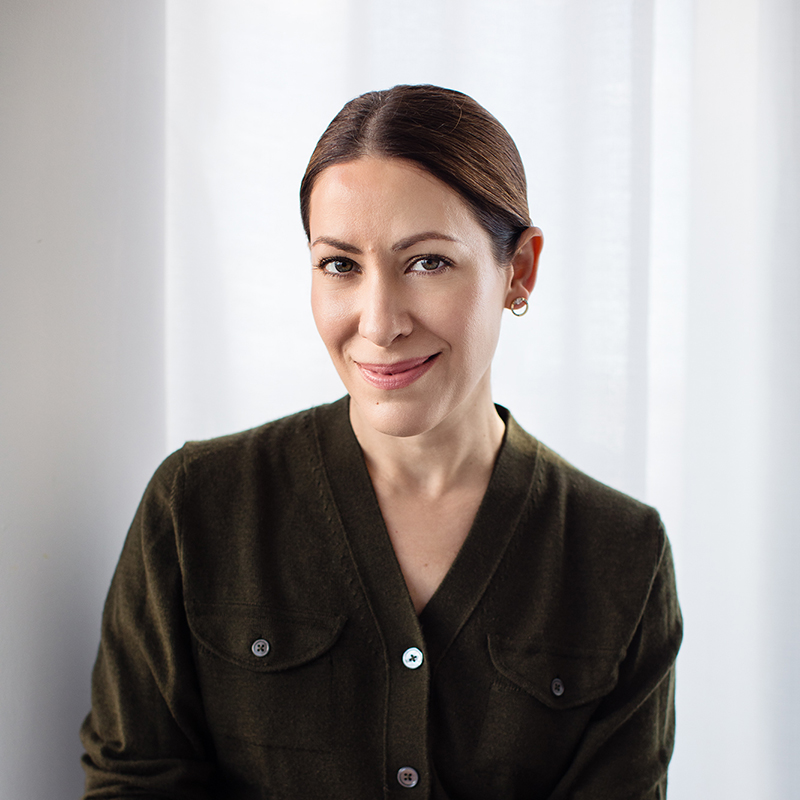 A woman smiling with her hair pulled back, wearing a green cardigan