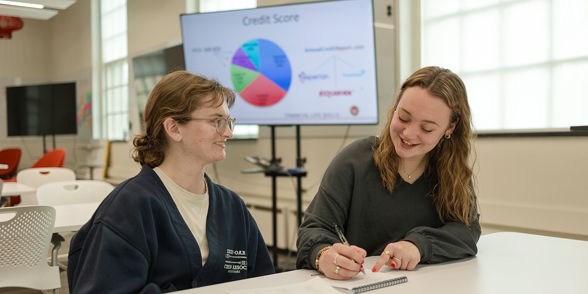 BadgerSense coach Alexis Swaney '26 meets with a student peer. A credit score pie chart is in the background.