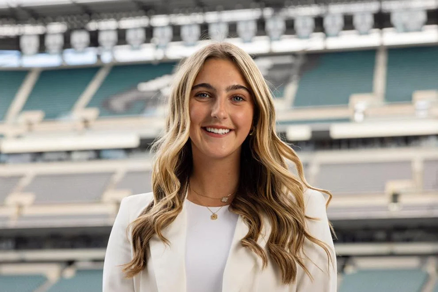 A blonde person smiling in a sports stadium