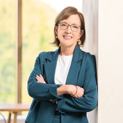 A white woman smiling with brown hair wearing a green suit