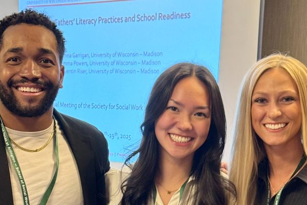 Quentin Riser, Emma Powers, and Genna Garrigan standing in front of a power point presentation.