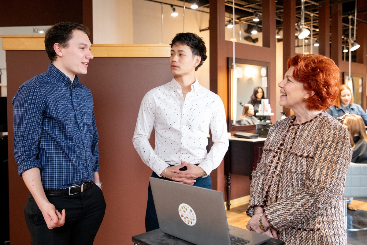Two students present to their client on site at the client's salon business.