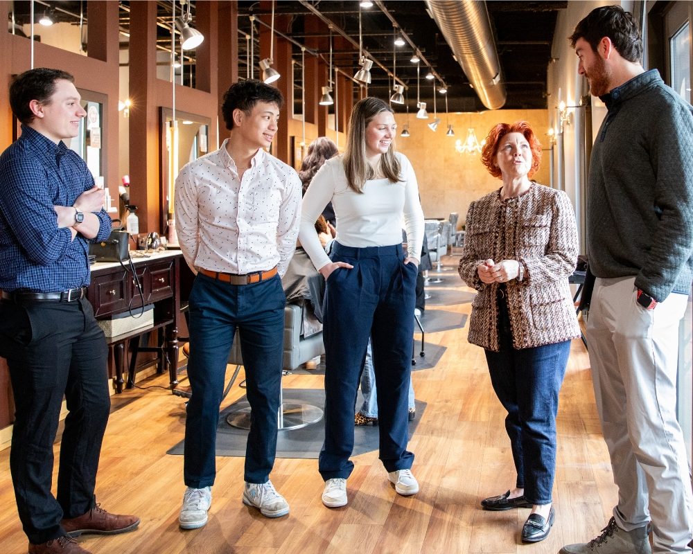 Four students talk with their business client on location at their salon.