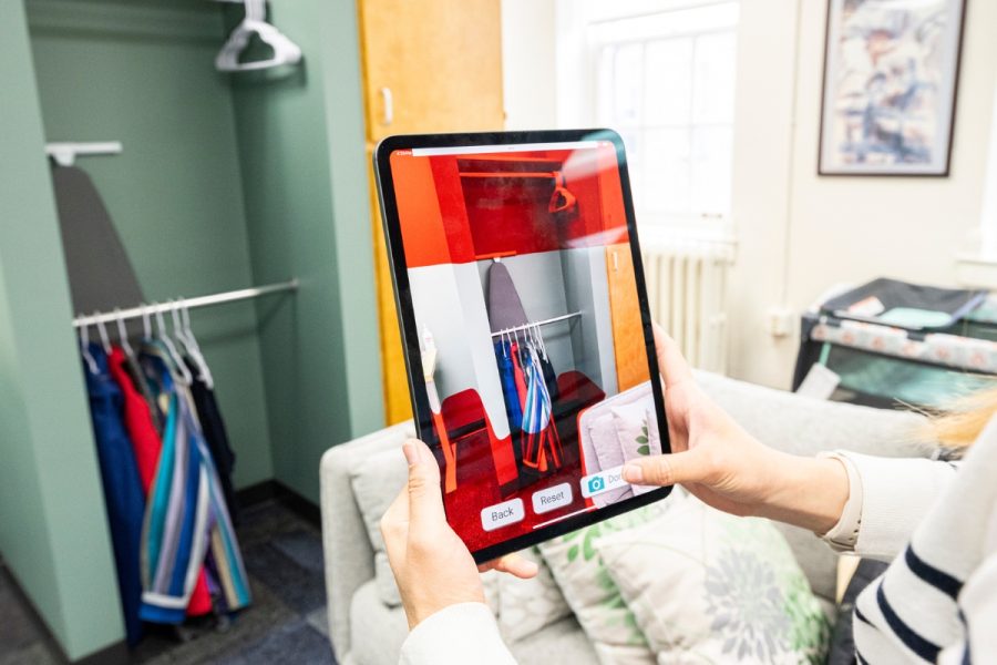 A person holding an iPad demonstrates how an augmented reality app is used to measure a closet shelf. Red highlights at the top and bottom of the screen are key indicators to the user.