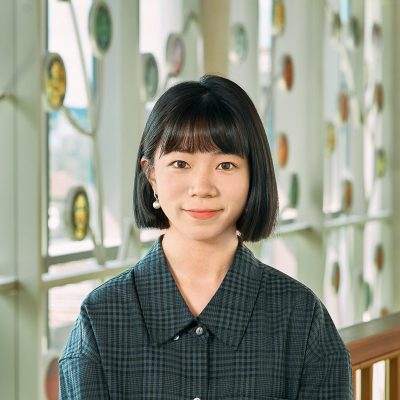 A Chinese woman，with black short hair and bangs，wearing a grey checked short.