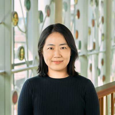 An Asian woman, with black short hair (shoulder-length), wearing a dark blue short sleeve shirt.