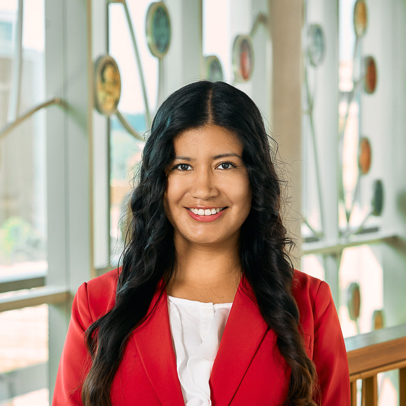 A latin woman smiling, with shoulder-length black hair, wearing a red jacket.