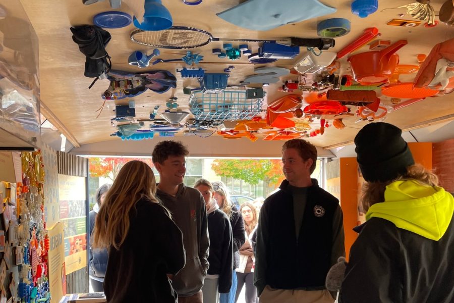A group of students inside a trailer with colorful trash on the ceiling and walls.