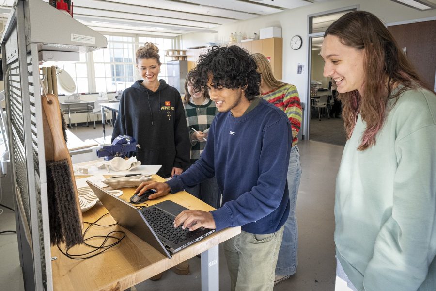 Design students gather around a laptop