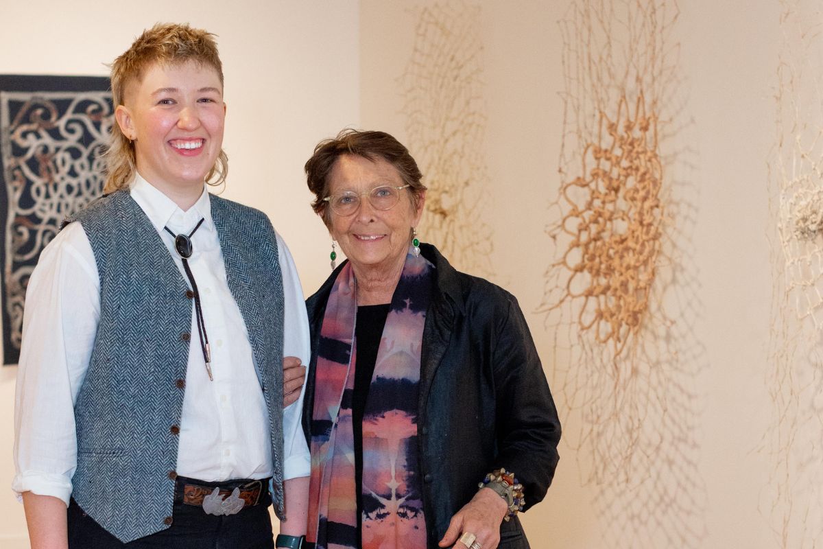 Two people pose arm-in-arm at a contemporary gallery space.