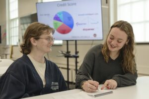 BadgerSense coach Alexis Swaney '26 meets with a student peer. A credit score pie chart is in the background.
