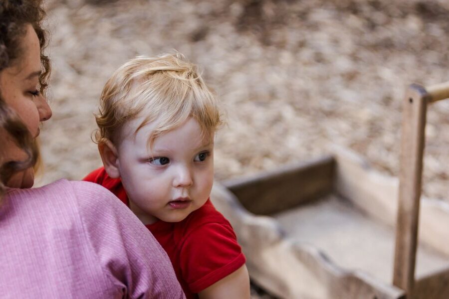An adult holds a toddler outdoors.
