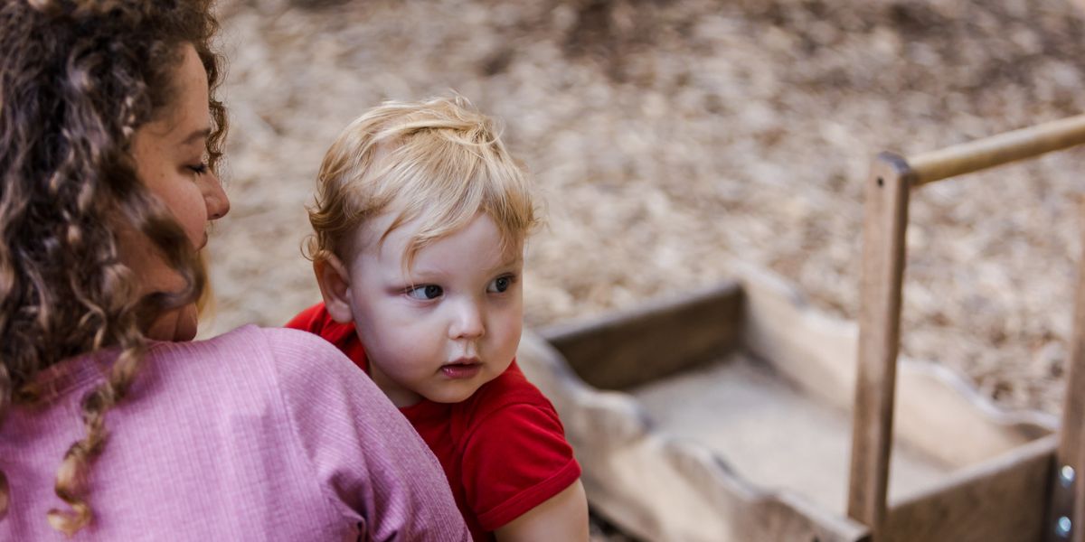 An adult holds a toddler outdoors.
