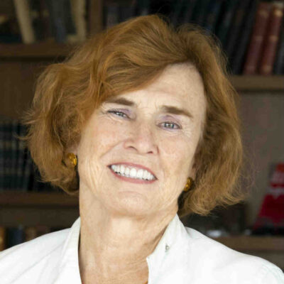white woman with freckles and reddish hair wearing a white top.